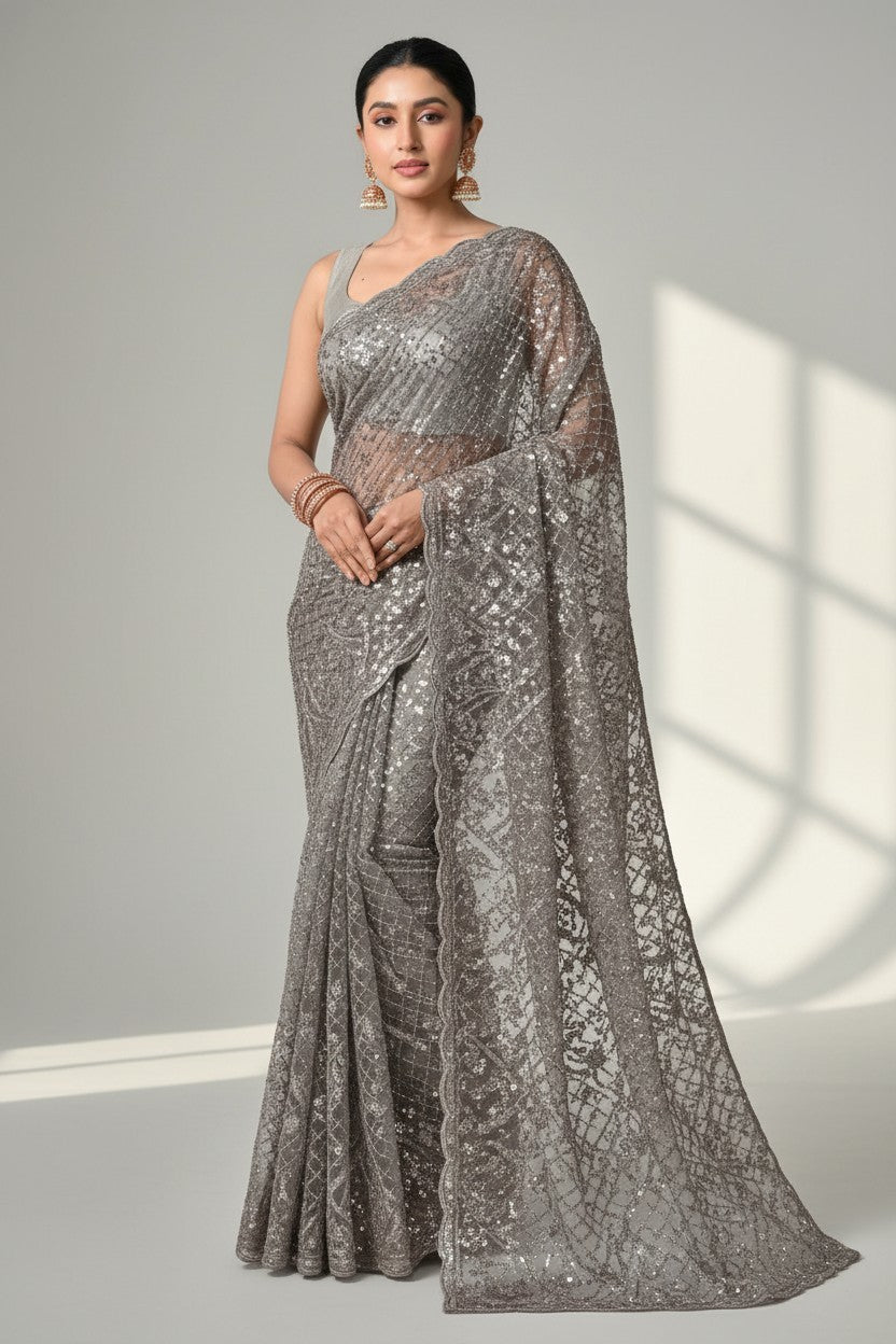 Rangoli grey net saree with all-over sequin embellishments and intricate border detailing. Model wears it for a special occasion.