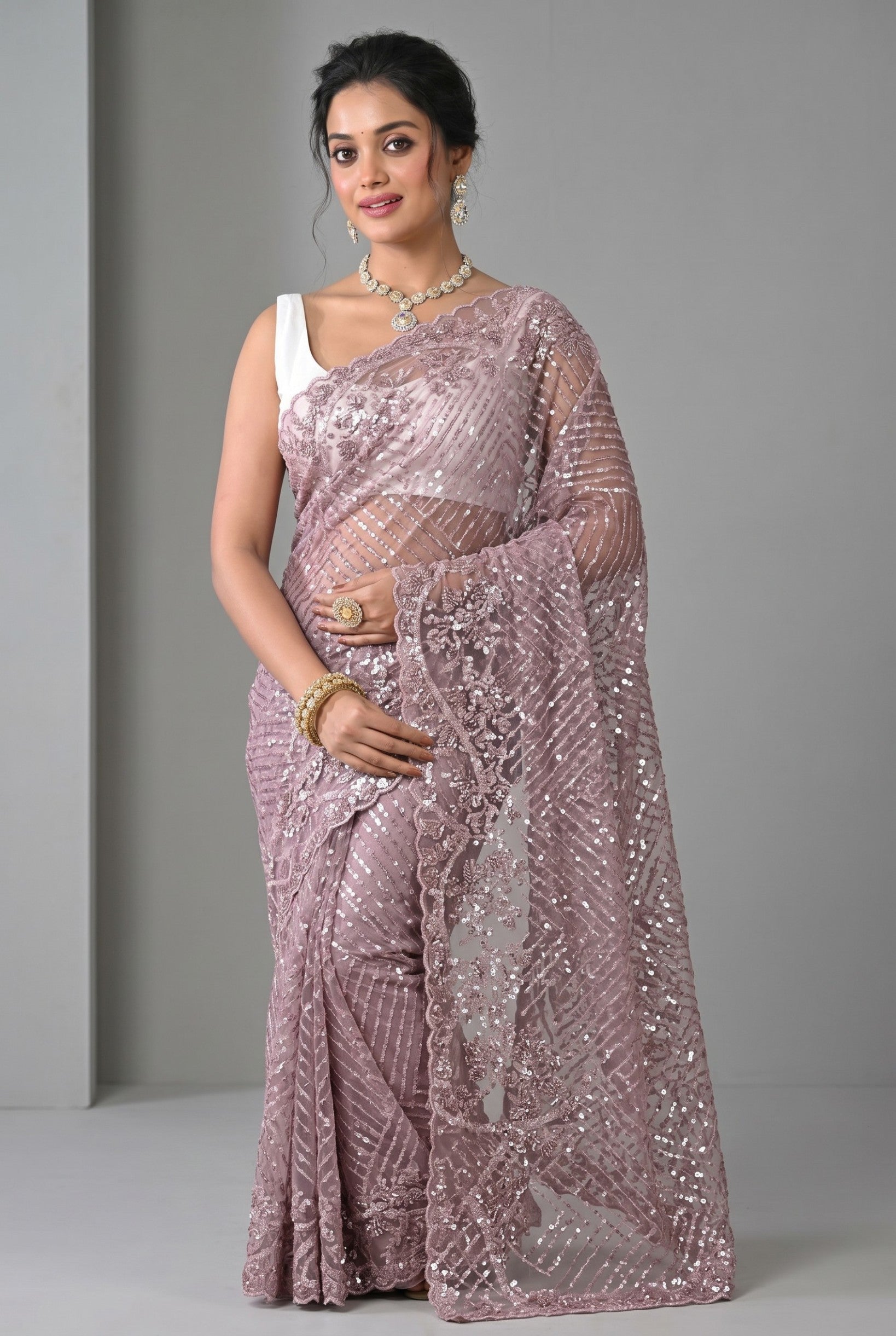 Rangoli lilac net saree with intricate sequin embellishments and floral border. Lightweight fabric with shimmering detail.