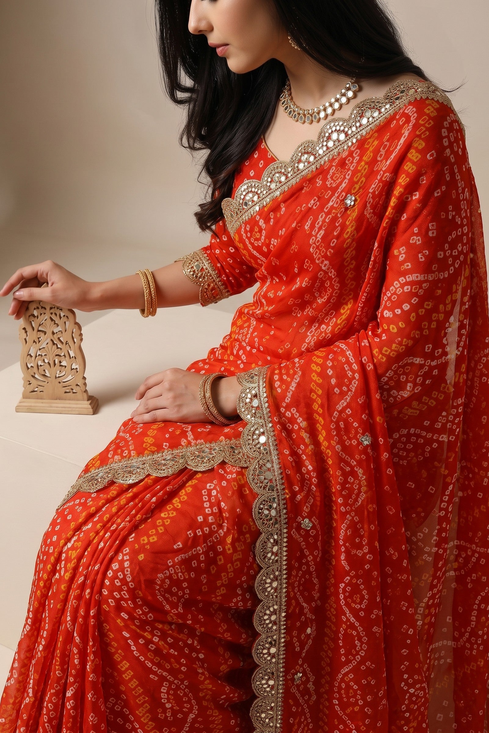 Rangoli orange silk saree with white and yellow bandhani tie-dye pattern. Features embroidered border with sequins and mirror work.