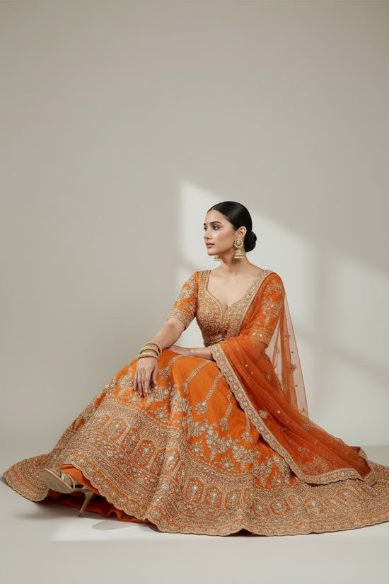 Rangoli orange silk lehenga with intricate embroidery, zari work, sequins, and net dupatta. Perfect for festive occasions.