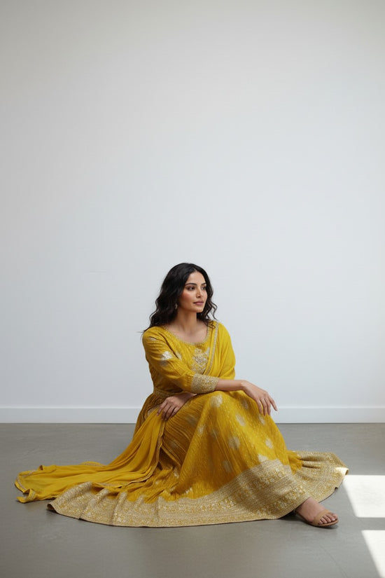 Rangoli yellow Anarkali suit with golden embroidery, three-quarter sleeves, and dupatta. Flowing fabric.