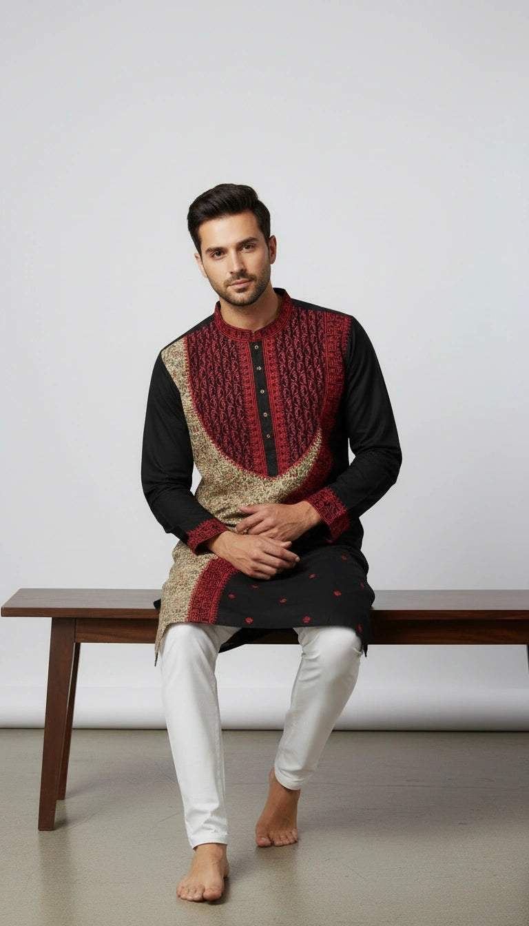 Man wearing a traditional outfit with a red and gold top and white pants, sitting on a wooden bench.