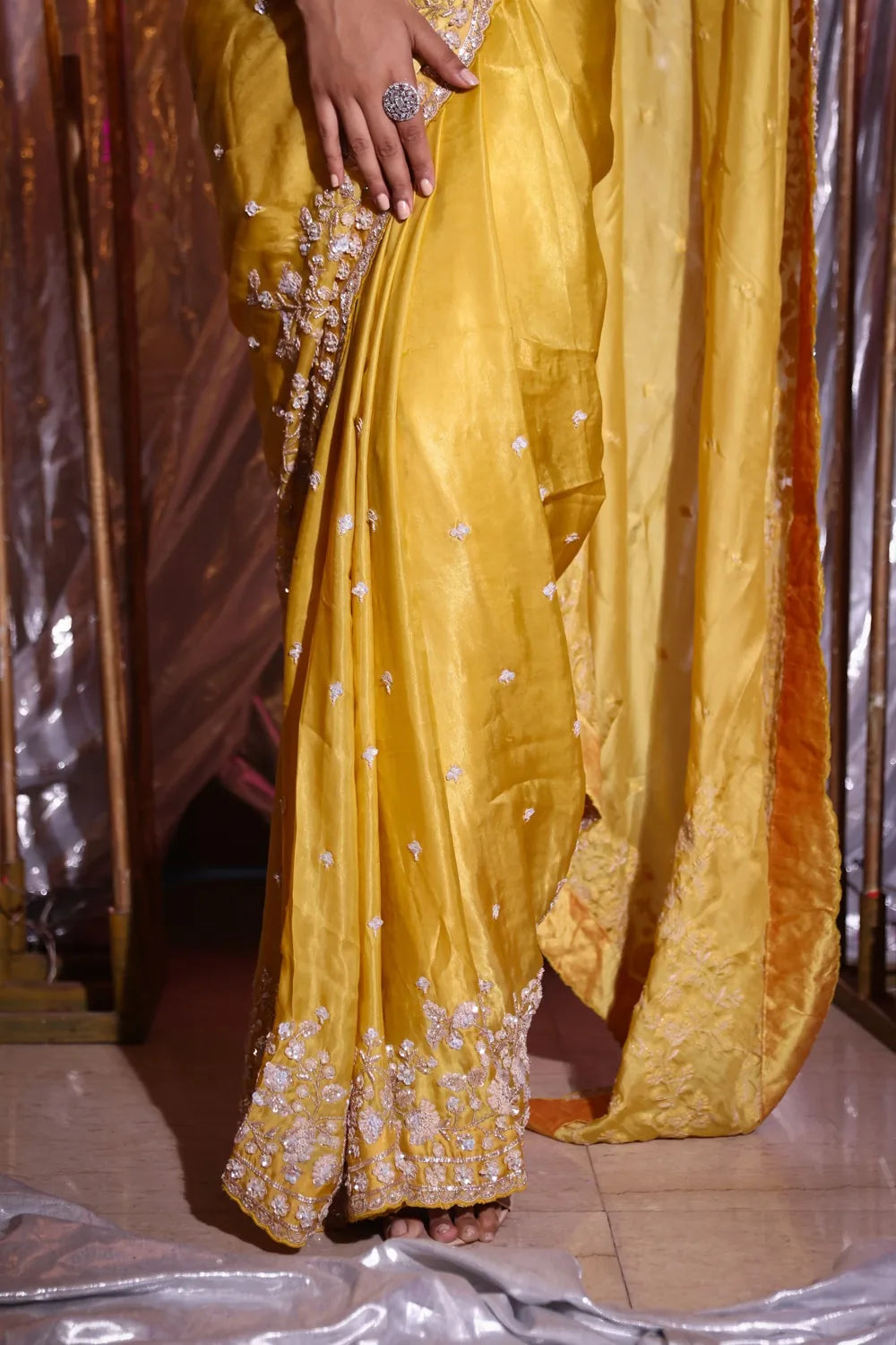 Yellow saree with intricate patterns on a reflective surface