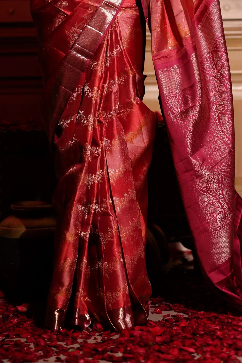 Red saree with gold patterns on a dark background