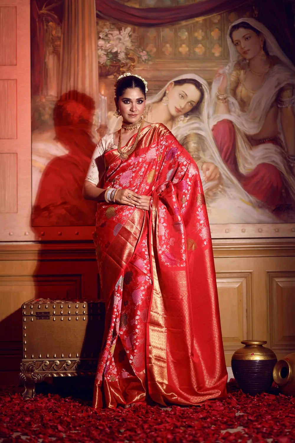 Woman in a red saree standing in front of a classical painting